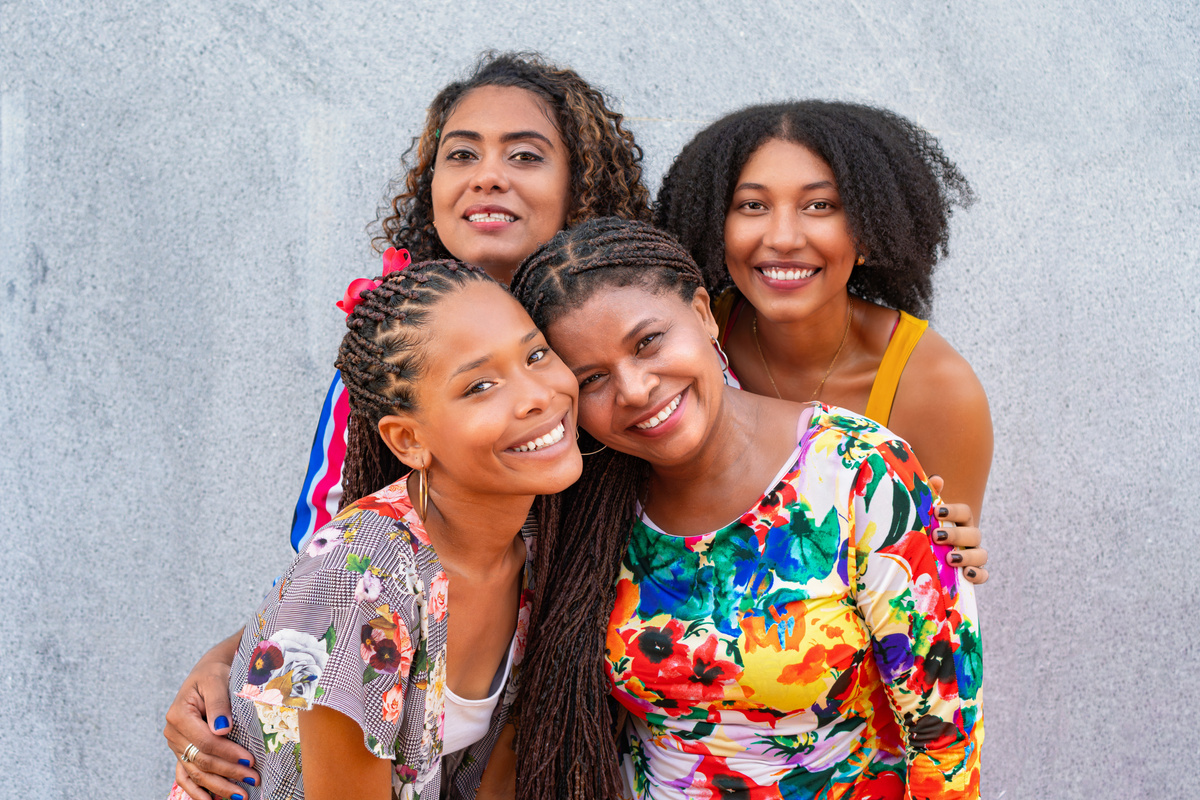 Portrait of four black women looking at the camera in front of a wall.